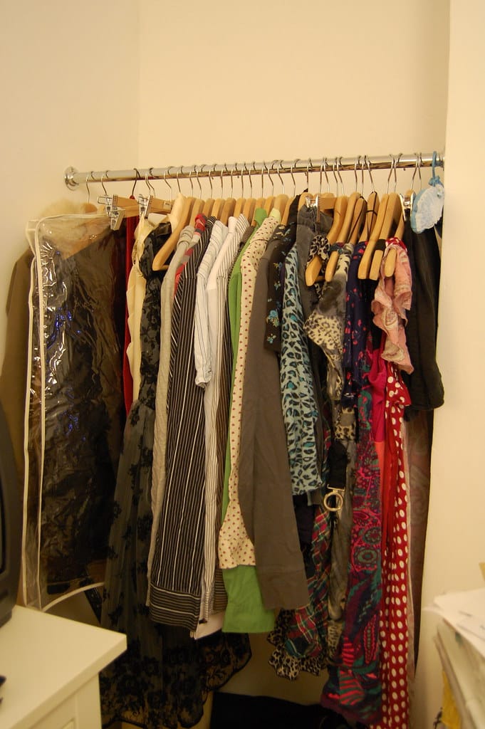 A narrow closet with clothes hung close together on a single rail