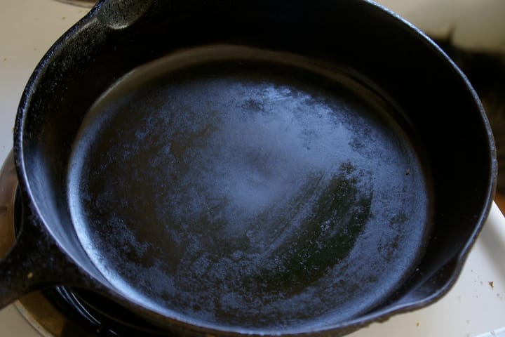 The cooking surface of a cast iron skillet with a thin film of oil wiped across it